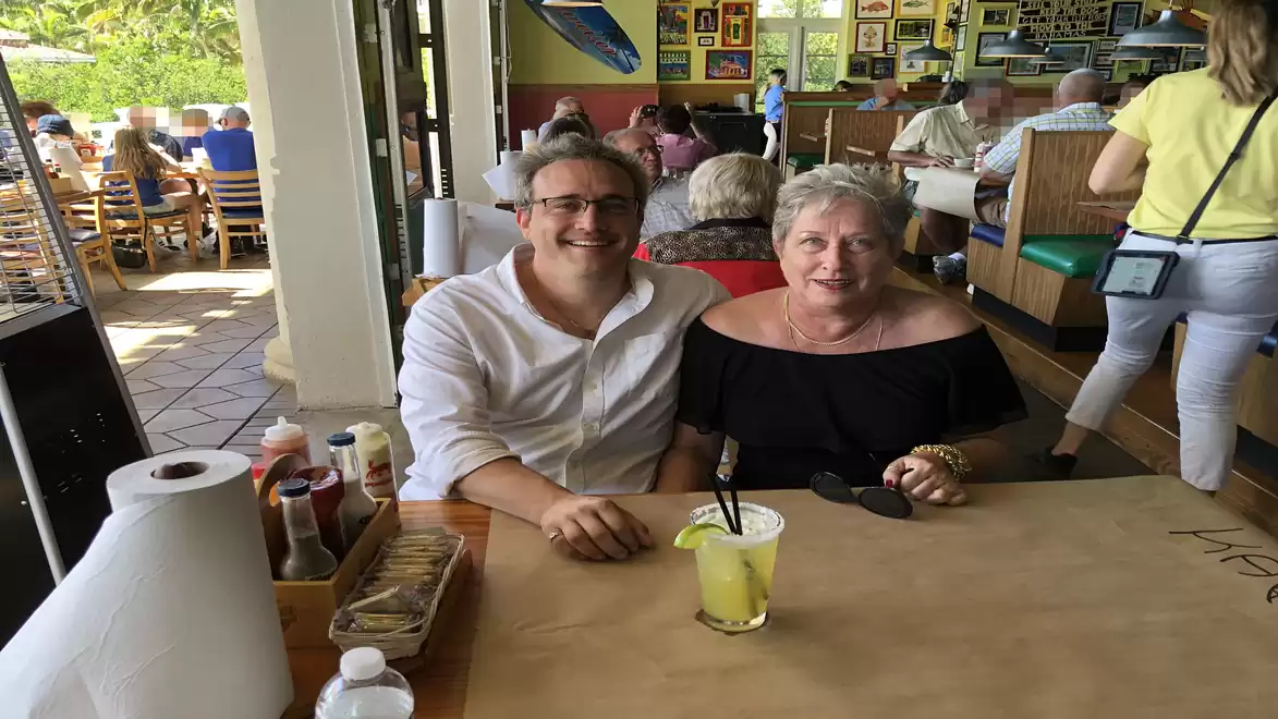 A man and a woman sitting at a table in a lively restaurant with other guests in the background.