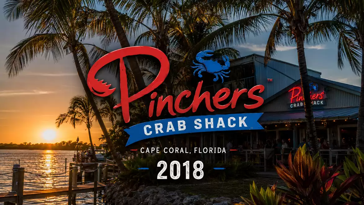 Sunset scene at Pinchers Crab Shack in Cape Coral, Florida, in 2018 with palm trees and a restaurant in the background.