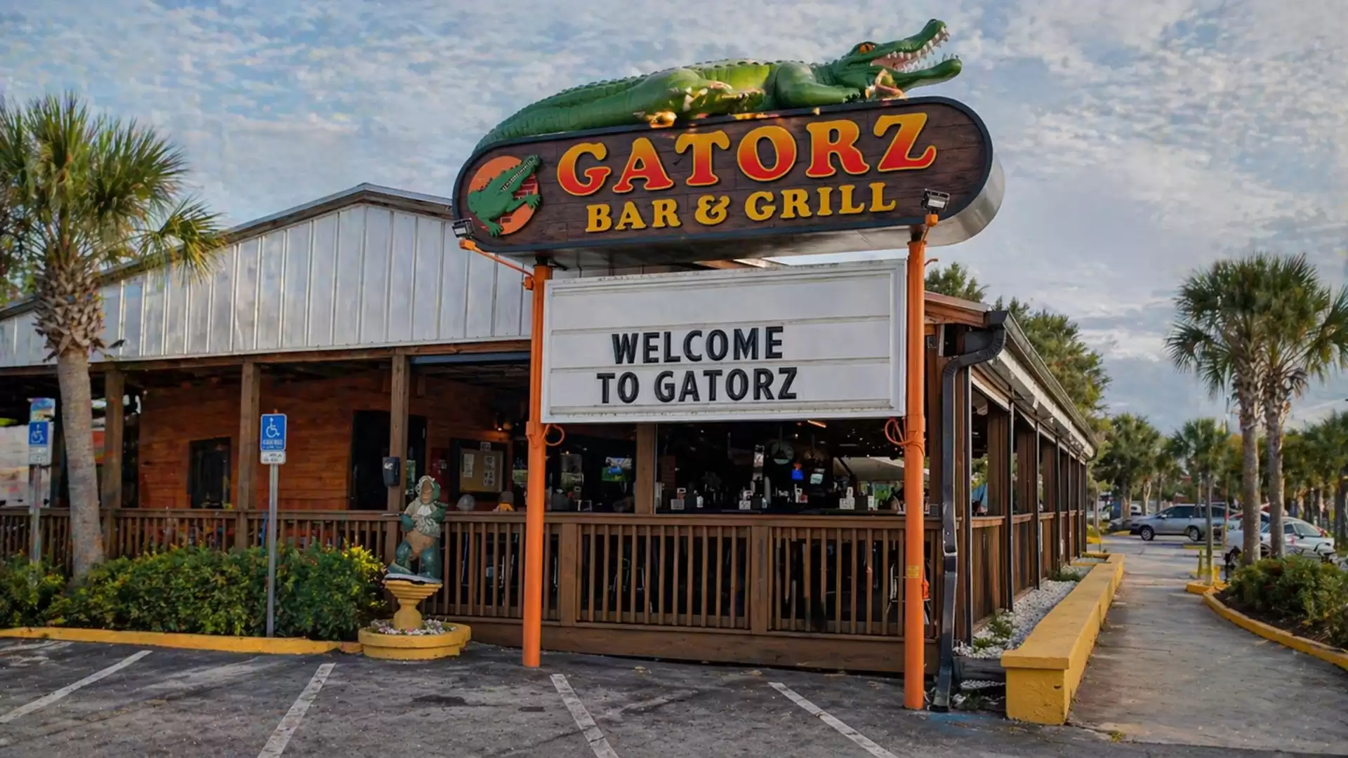 Exterior view of Gatorz Bar & Grill with a large sign and palm trees in the background.