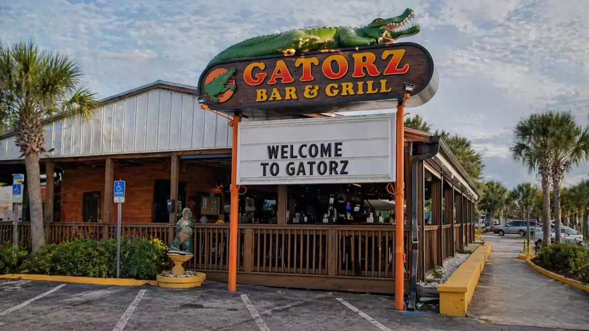 Exterior view of Gatorz Bar & Grill with a large sign and palm trees in the background.