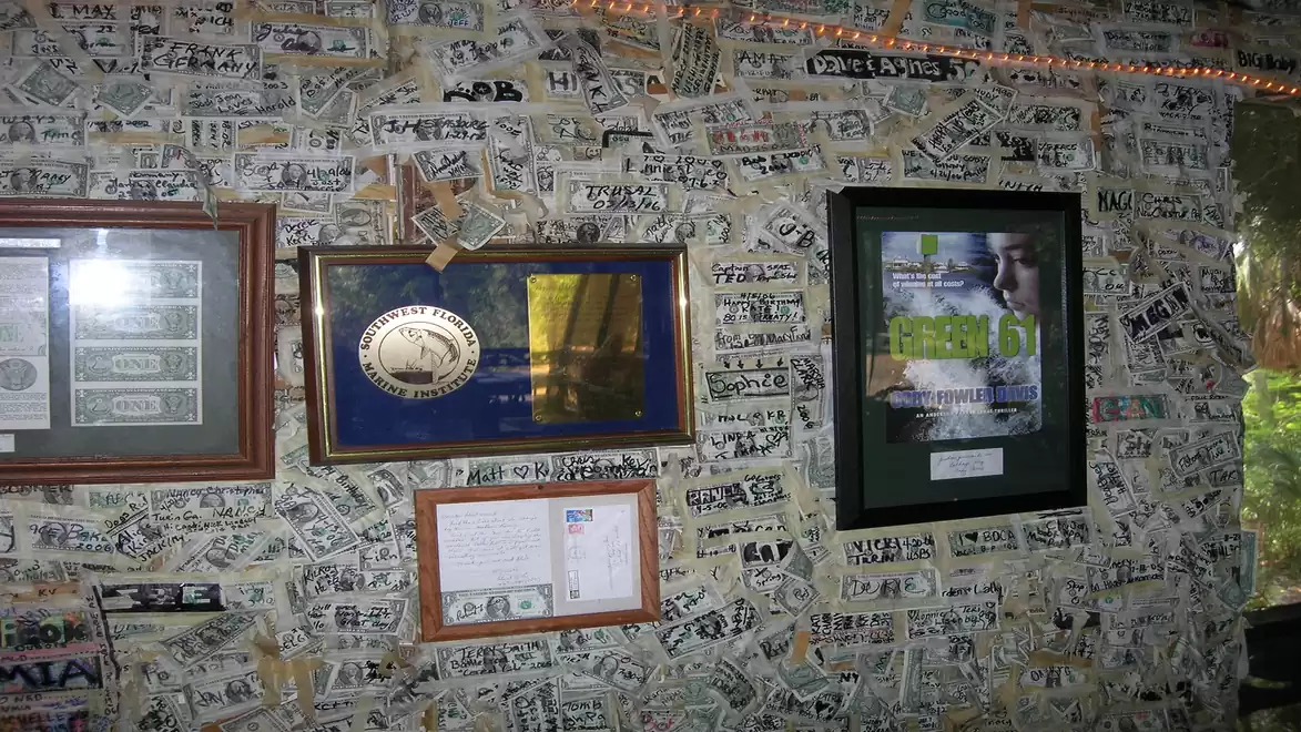 Wall with framed awards and banknotes; numerous handwritten notes.