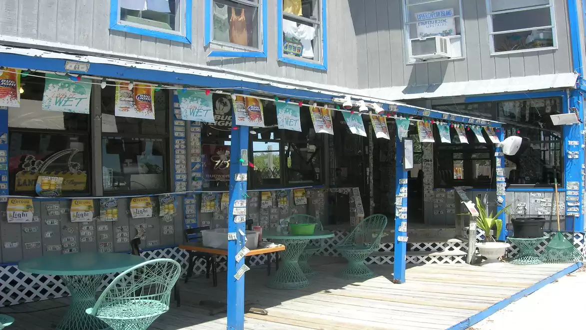 A cozy café with blue and white accents, decorated with colorful banners and green chairs, creating an inviting atmosphere.