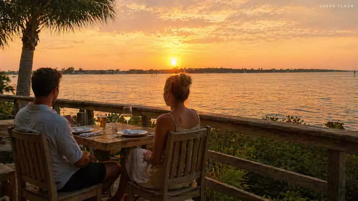 A couple enjoying an outdoor dinner overlooking the sunset over a calm lake.