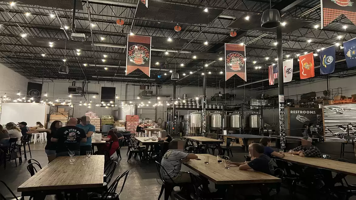 Interior view of a cozy brewery with seating and decorations on the ceiling.