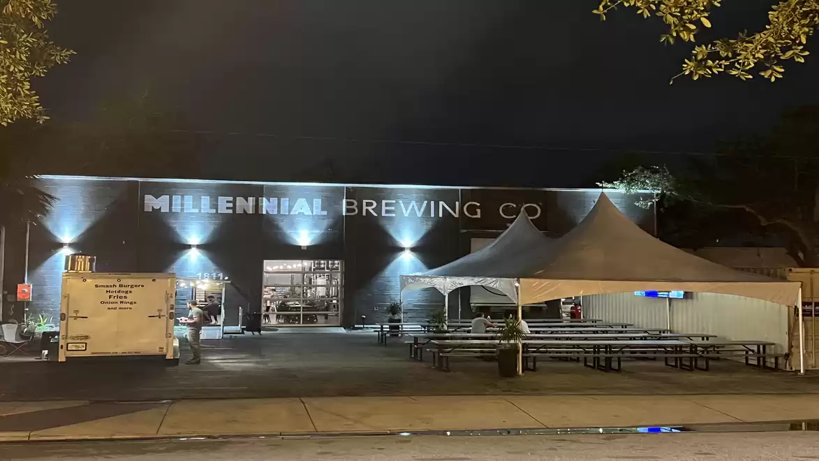 Exterior view of Millennial Brewing Co at night, illuminated with a large tent in front of the building.