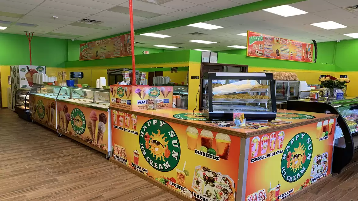A vibrant ice cream shop with colorful walls, a long counter, and a wide variety of ice creams.