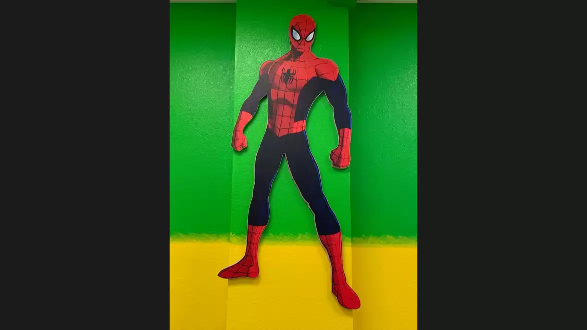 Image of a Spiderman figure on a colorful background with green and yellow stripes.