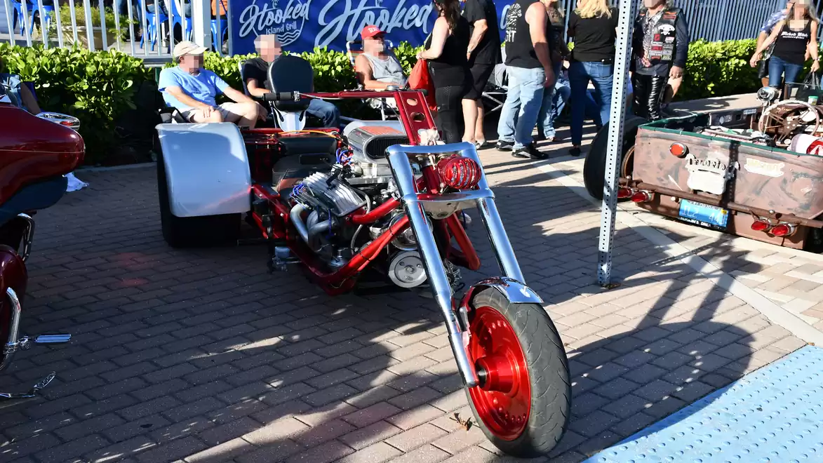A red motorcycle on display with several people in the background.