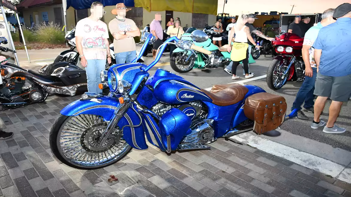 Blue motorcycle at an outdoor event with a crowd in the background.