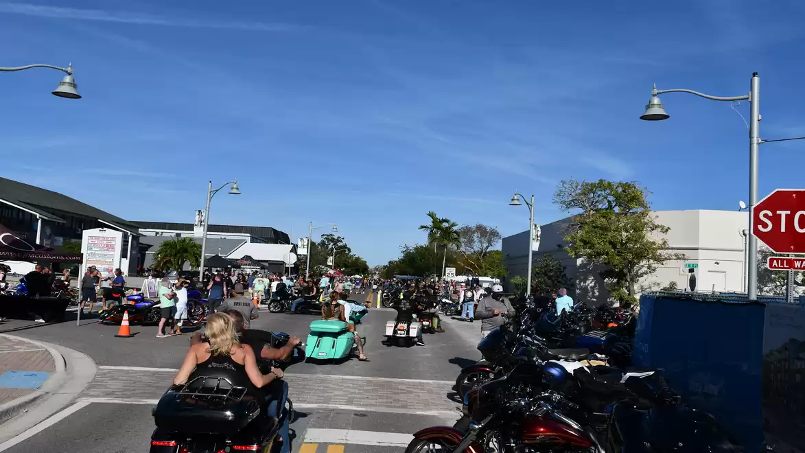 A busy street filled with motorcycles and people under sunny weather at a motorcycle event.