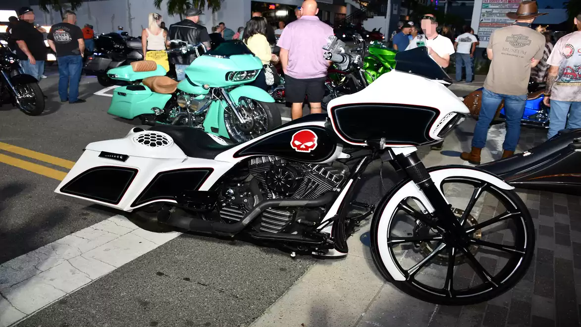 A custom-designed motorcycle with striking black-and-white design and red accents, surrounded by people at an urban street event.