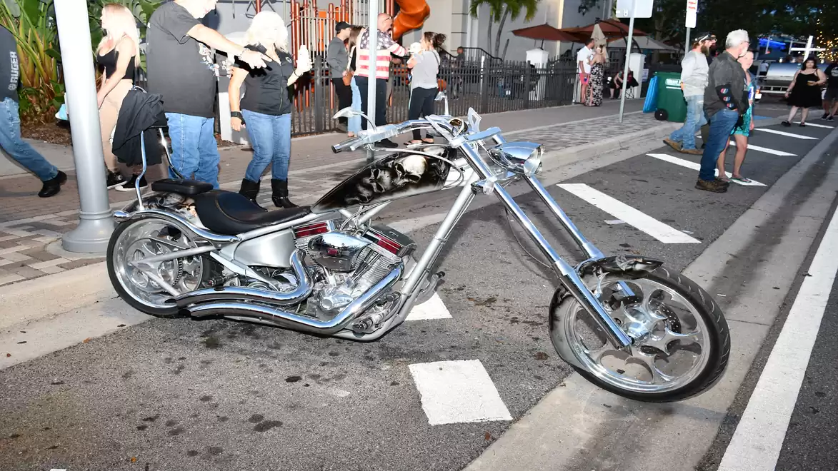 An impressive silver custom motorcycle parked on a street, surrounded by people at an event.