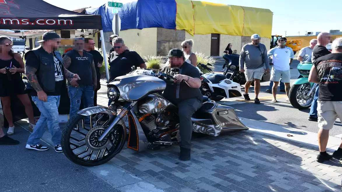 A group of people gathered around a striking motorcycle at an exhibition. Various motorcycles are visible in the background.