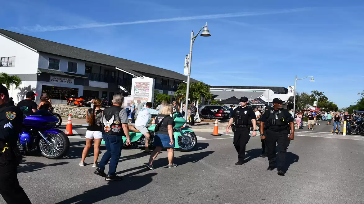 Street scene with people and police officers on a sunny day in a city.