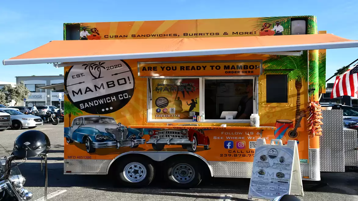 Vibrant food truck offering Cuban sandwiches and burritos. Colorful design featuring car and palm tree motifs.