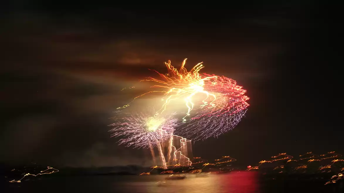 A colorful fireworks display lights up the night sky over a body of water.