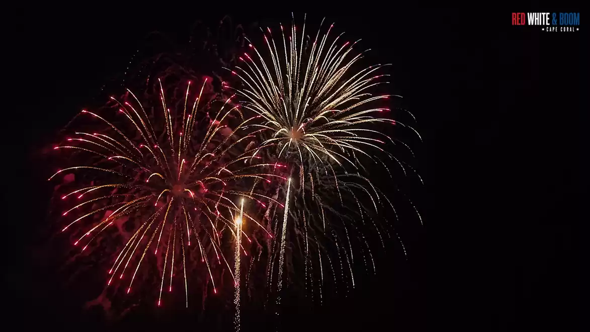 A colorful fireworks display lights up the night sky with red and white sparks.