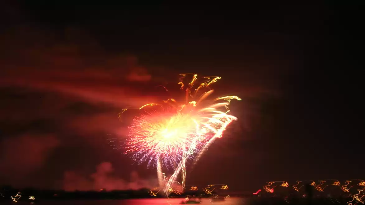 Colorful fireworks bursting against a dark night sky, reflecting on the water.