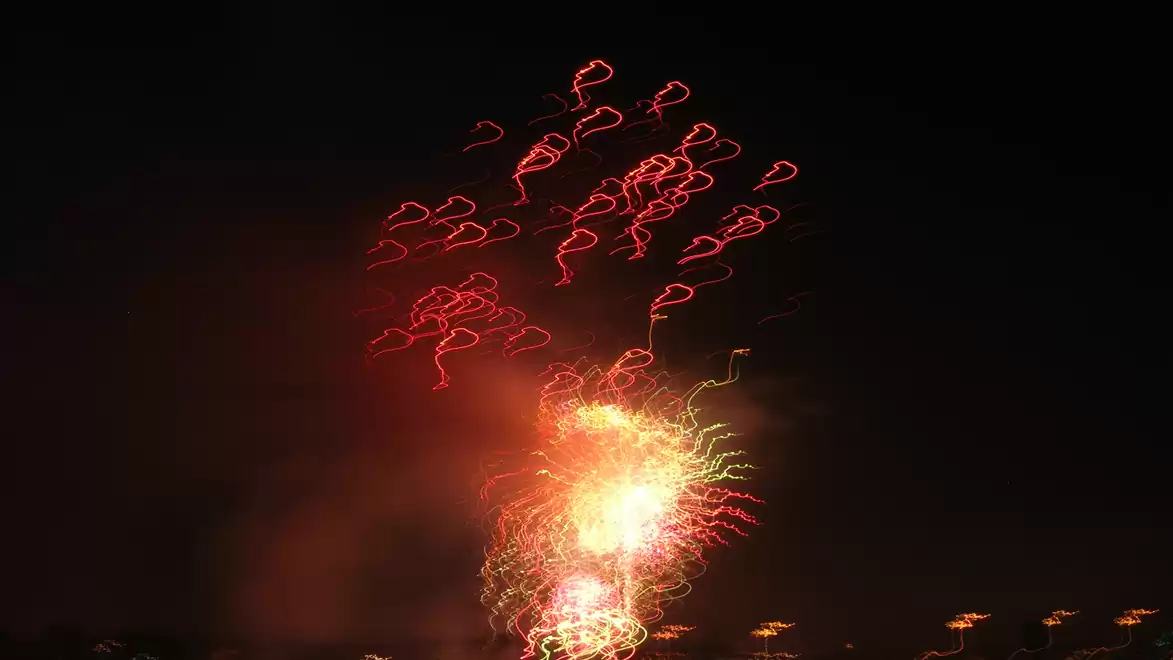 Night fireworks with red and yellow lights in the sky forming heart shapes.
