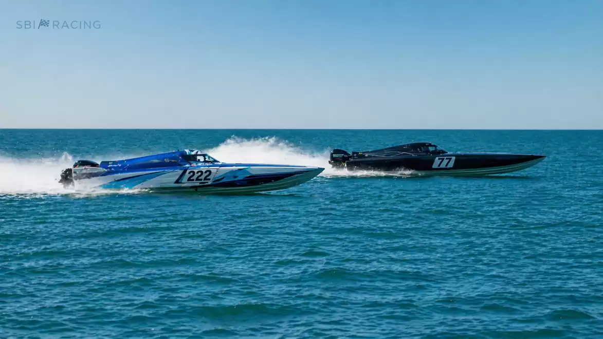Two racing boats speed side by side on open water under a clear sky.