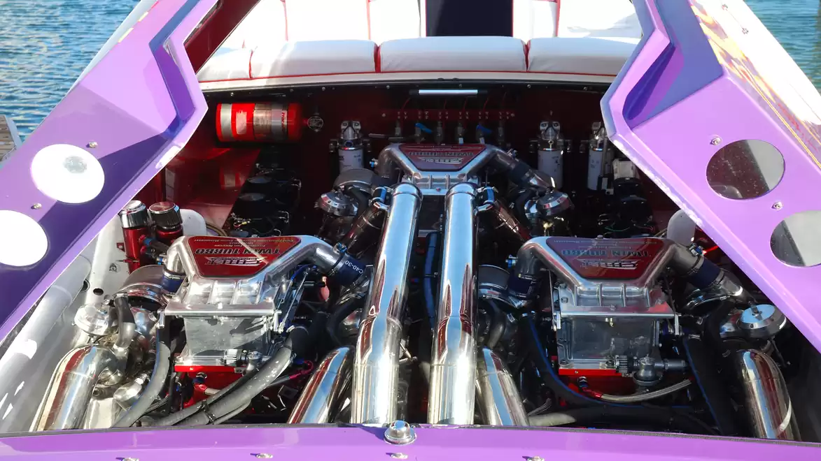 Close-up of a powerful boat interior featuring two large engines and a purple cover.