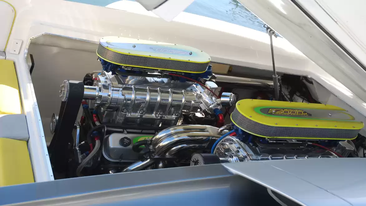 Large and powerful engine in an open engine compartment of a boat, surrounded by shiny metal parts.