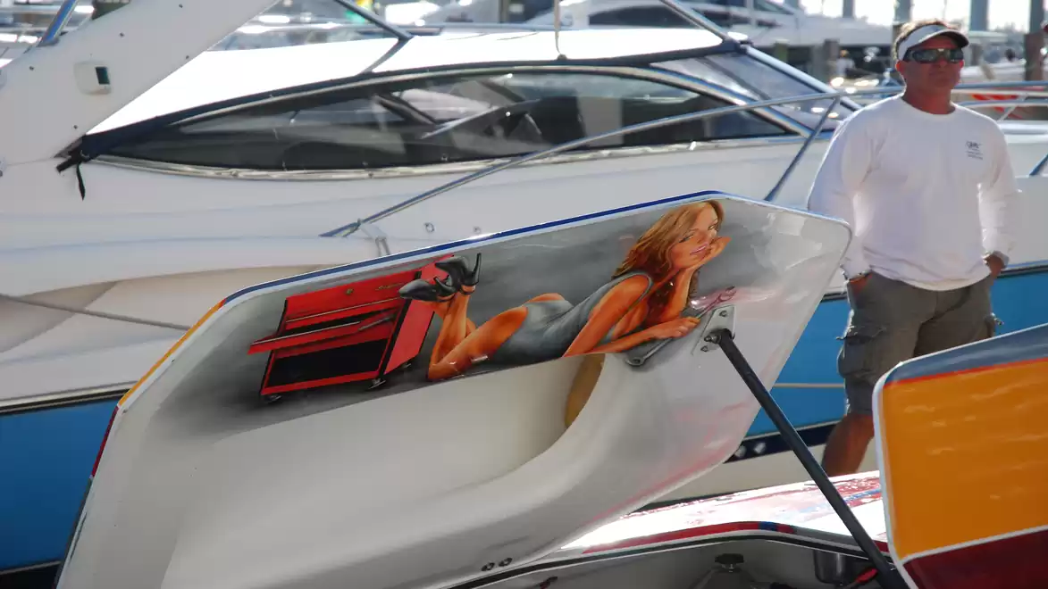 A boat in the harbor with a painted engine cover depicting a woman in swimwear.