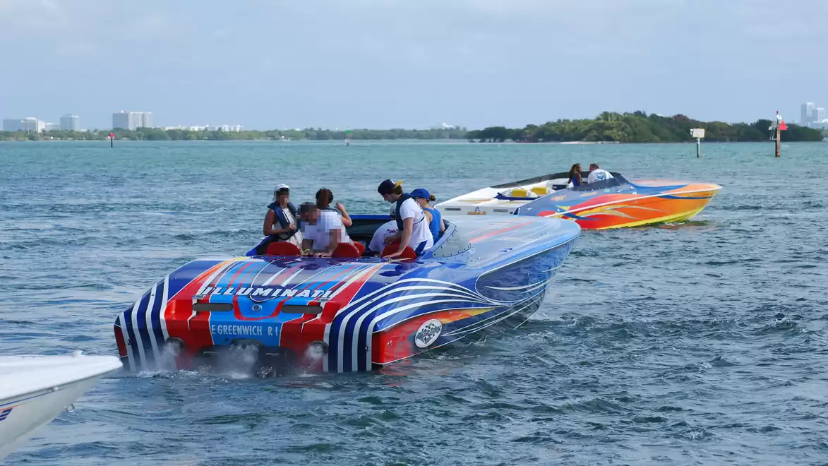Three colorful powerboats cruising on open water in sunny weather.