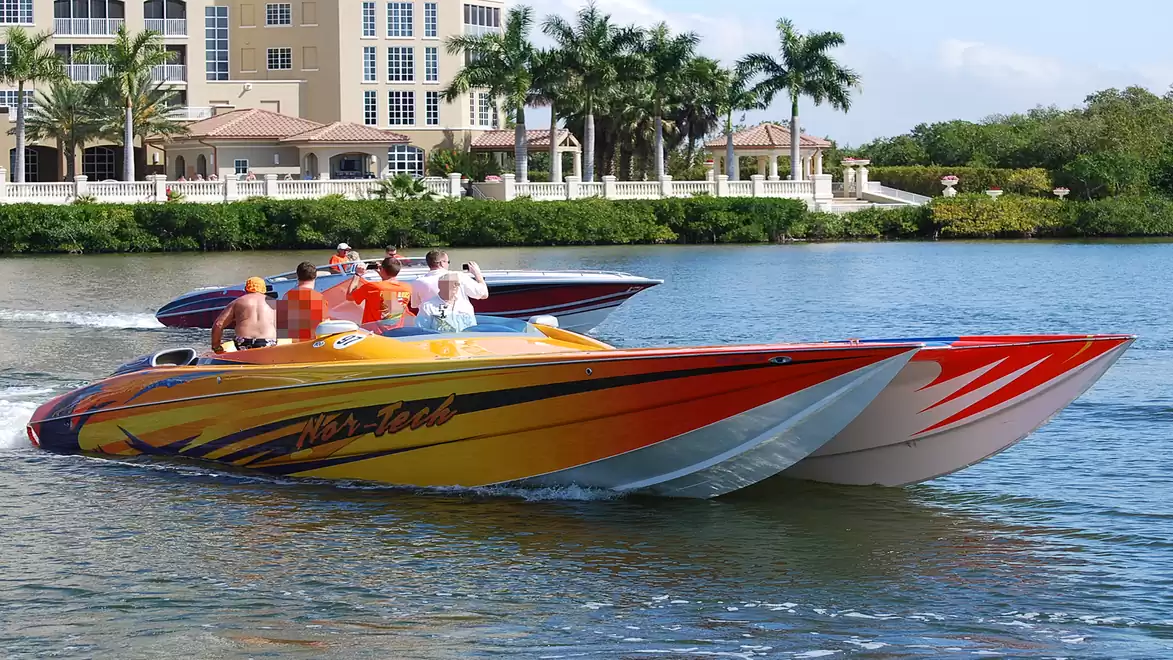 Two colorful racing boats on a river with a luxurious building in the background.