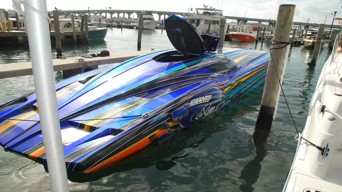 Colorful speedboat in the harbor with modern paint job and futuristic design, docked at a marina on a sunny day.