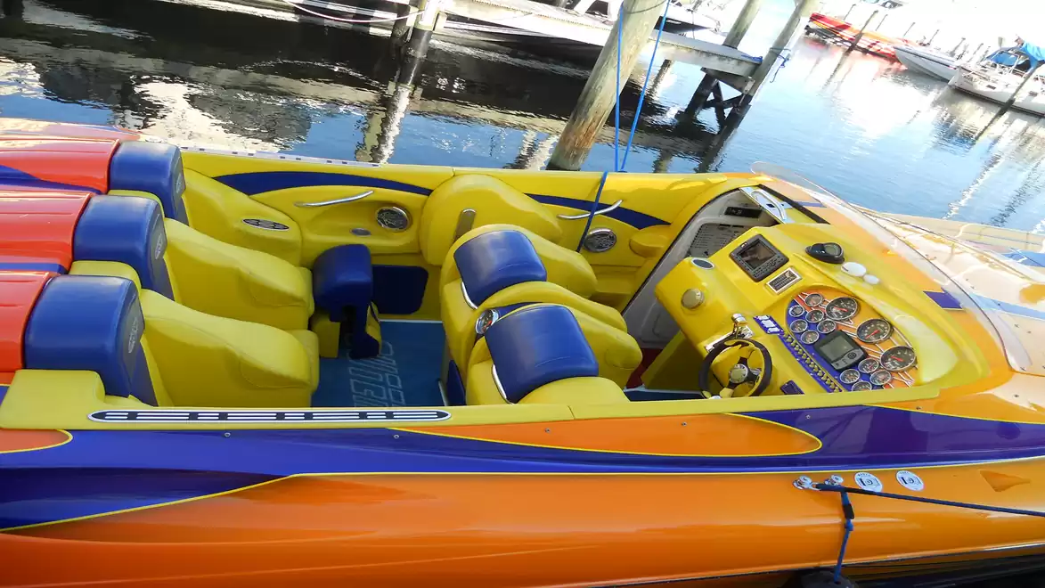 Colorful speedboat with yellow seats and blue-orange design moored at the dock.
