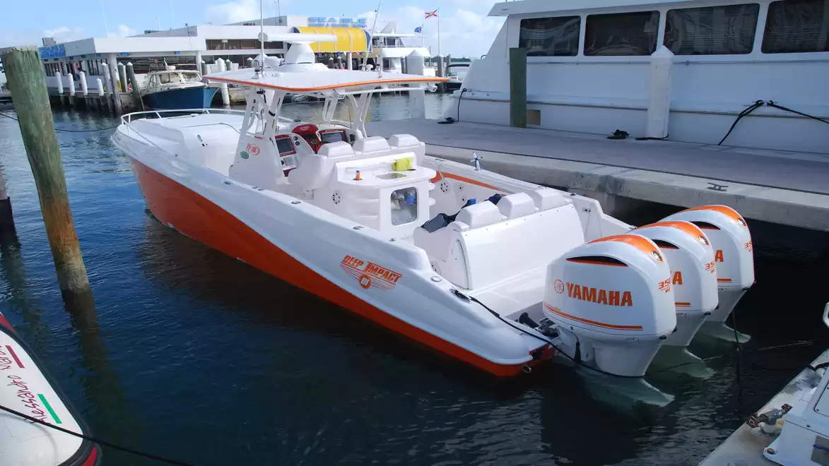 A fast motorboat with three Yamaha outboard engines docked in a marina.
