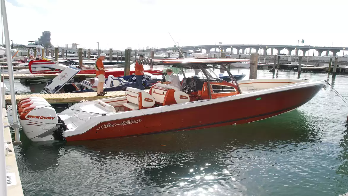 A fast outboard motor by Mercury on a red speedboat in the harbor on a sunny day.