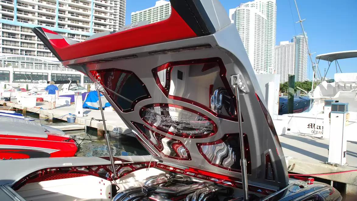Open engine hood of a luxurious speedboat in the harbor, surrounded by modern buildings.