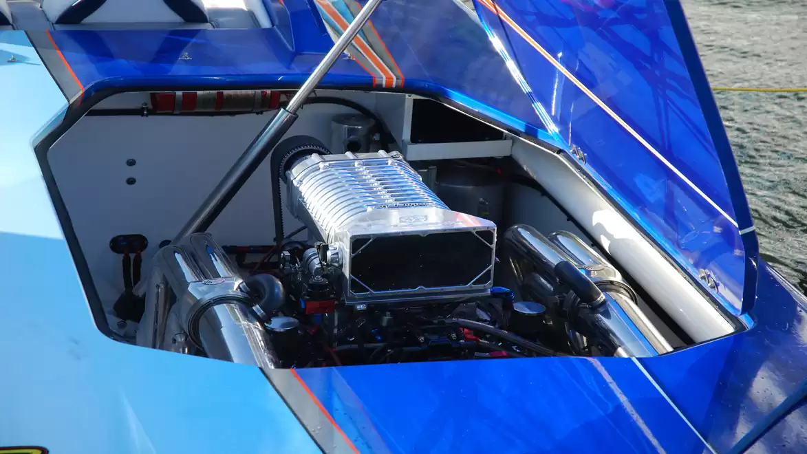 Close-up of a powerful engine in a blue speedboat with the hood open.