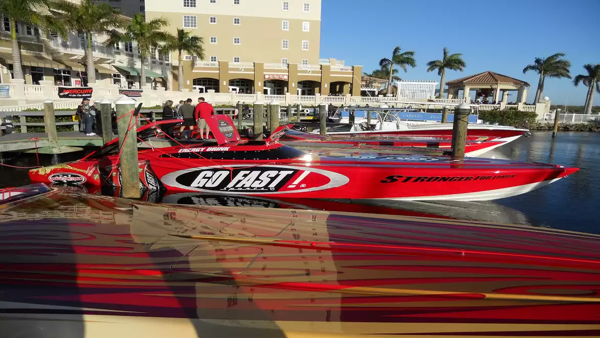 Red racing boats at the pier with palm trees in the background.