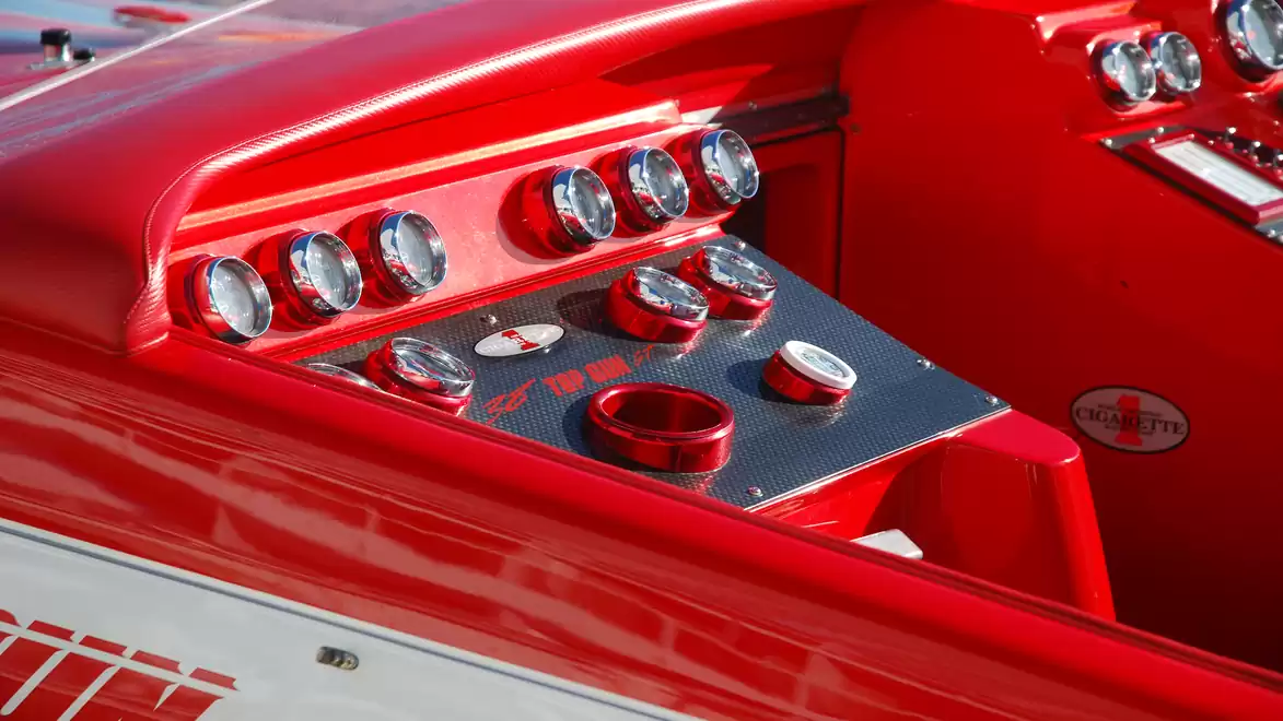 Close-up of a red speedboat cockpit with shiny gauges and control knobs.