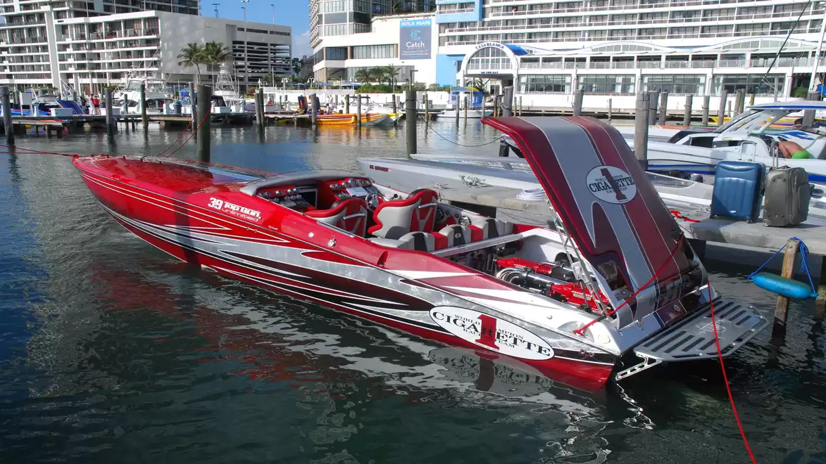 Red and white speedboat at a marina with an open deck lid.