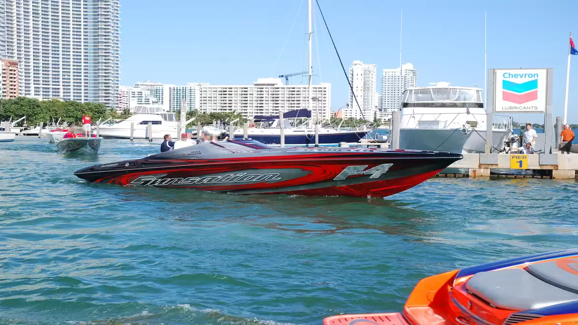 Speedboat on the water with skyscrapers in the background, near a Chevron station at the dock.