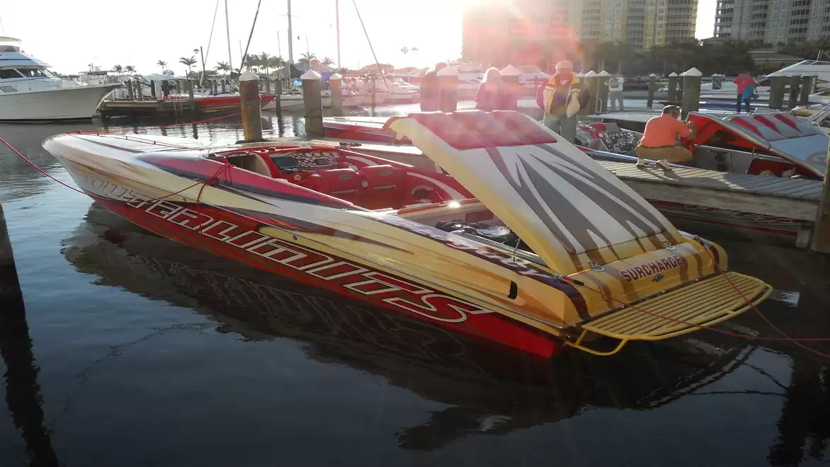 A sporty speedboat is docked in the harbor and illuminated by sunlight.