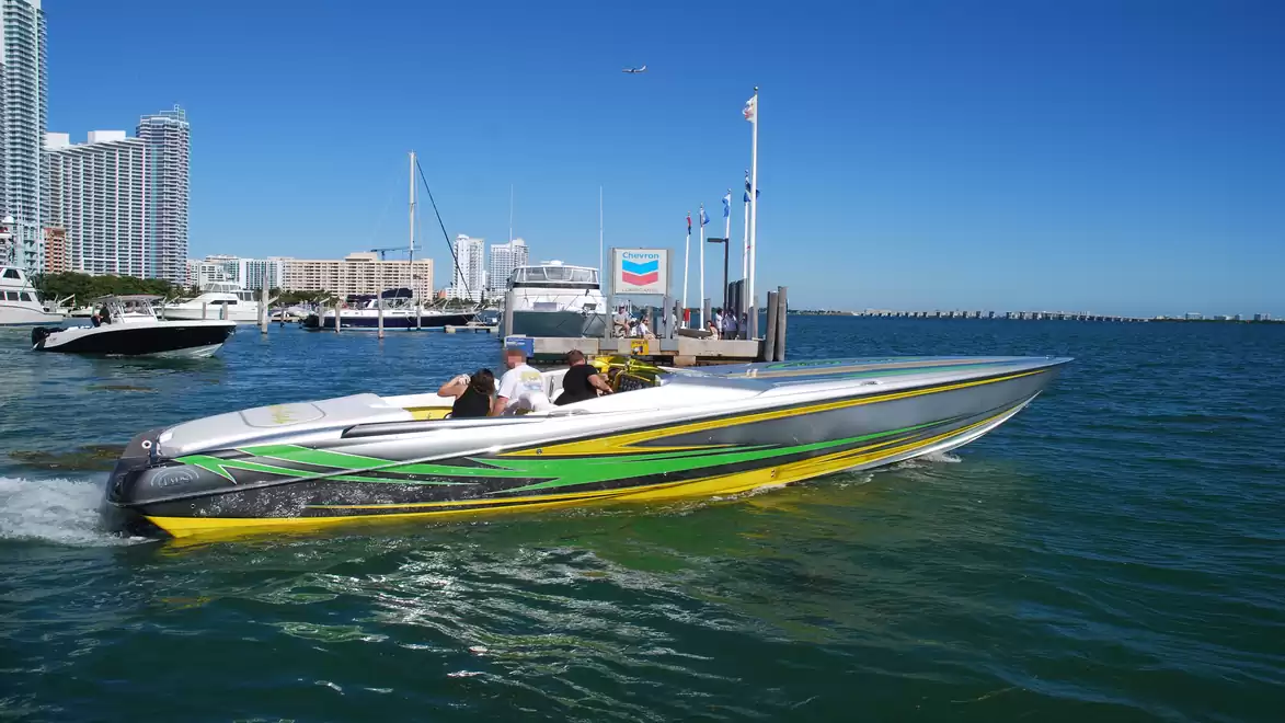 Speedboat on the water in a marina, with a modern skyline in the background.
