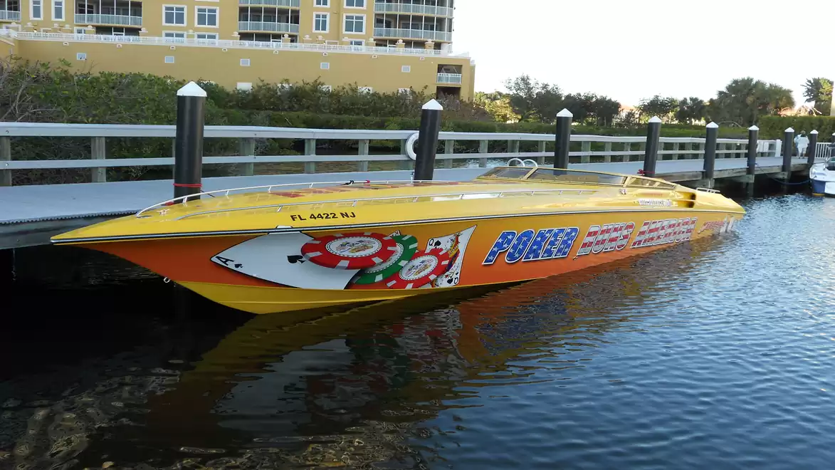 Yellow speedboat with poker graphics docked at a pier.