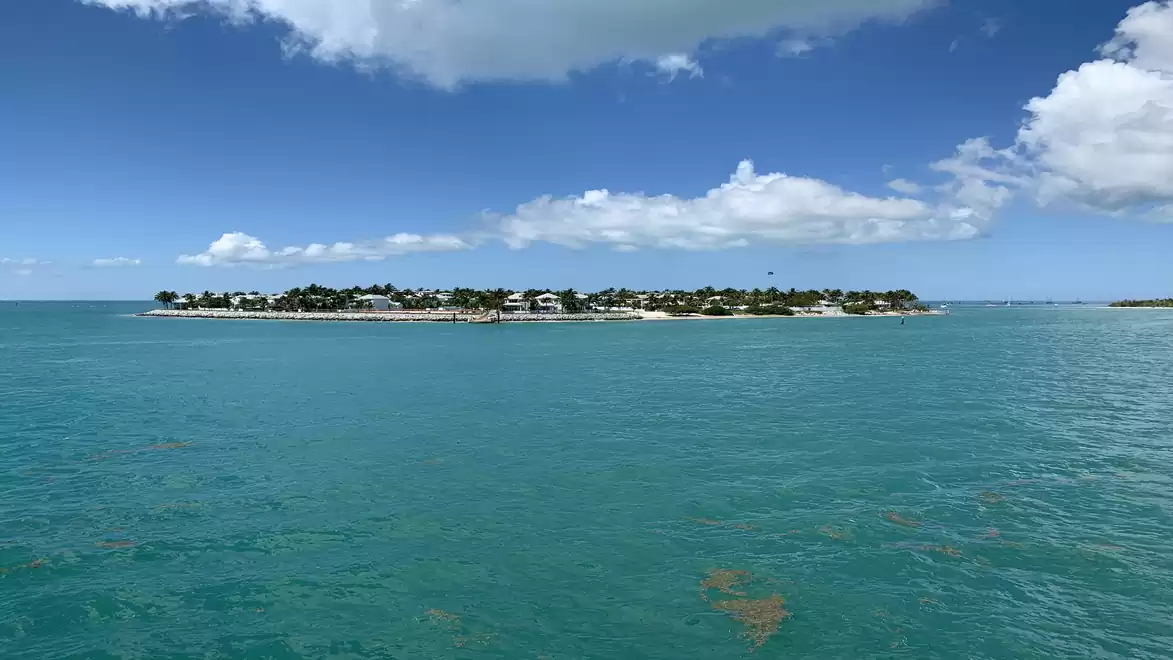 Panoramic view of an island in the sea under a blue sky with white clouds.