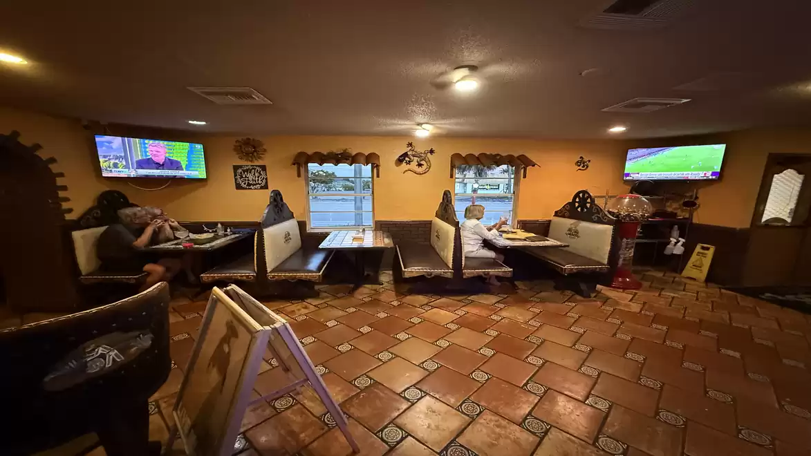 Cozy restaurant with traditional tiles, several TVs on the walls showing sports broadcasts, and guests dining in separate booths.