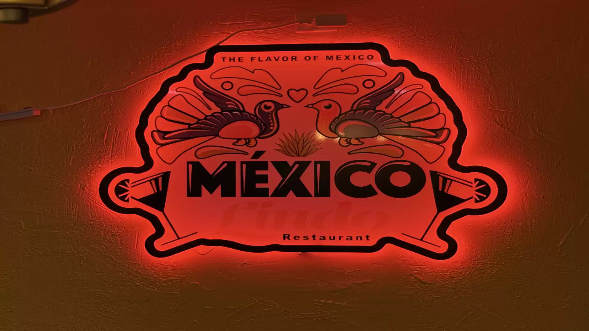 Illuminated sign of a Mexican restaurant featuring two stylized birds and the text 'Mexico'.