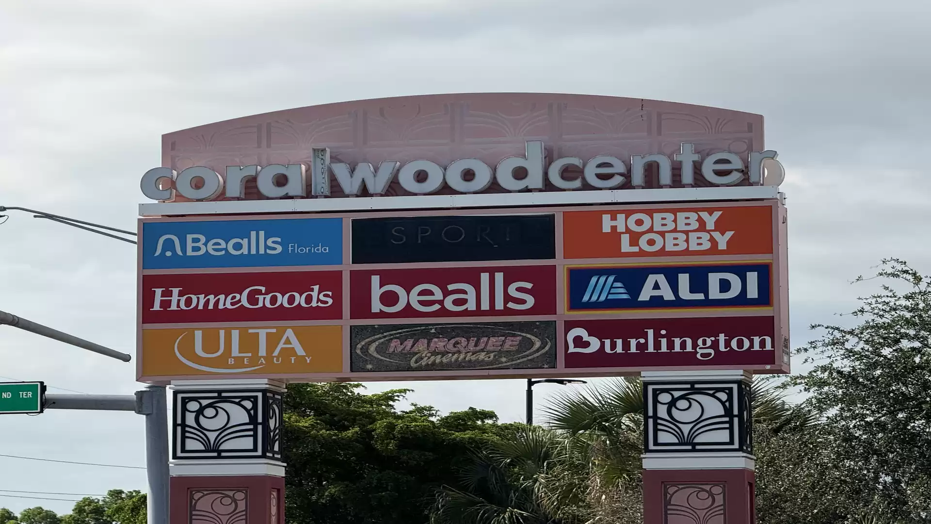 Image of a shopping center sign with logos of various stores like Hobby Lobby, Aldi, and Burlington, labeled as Coralwood Center.