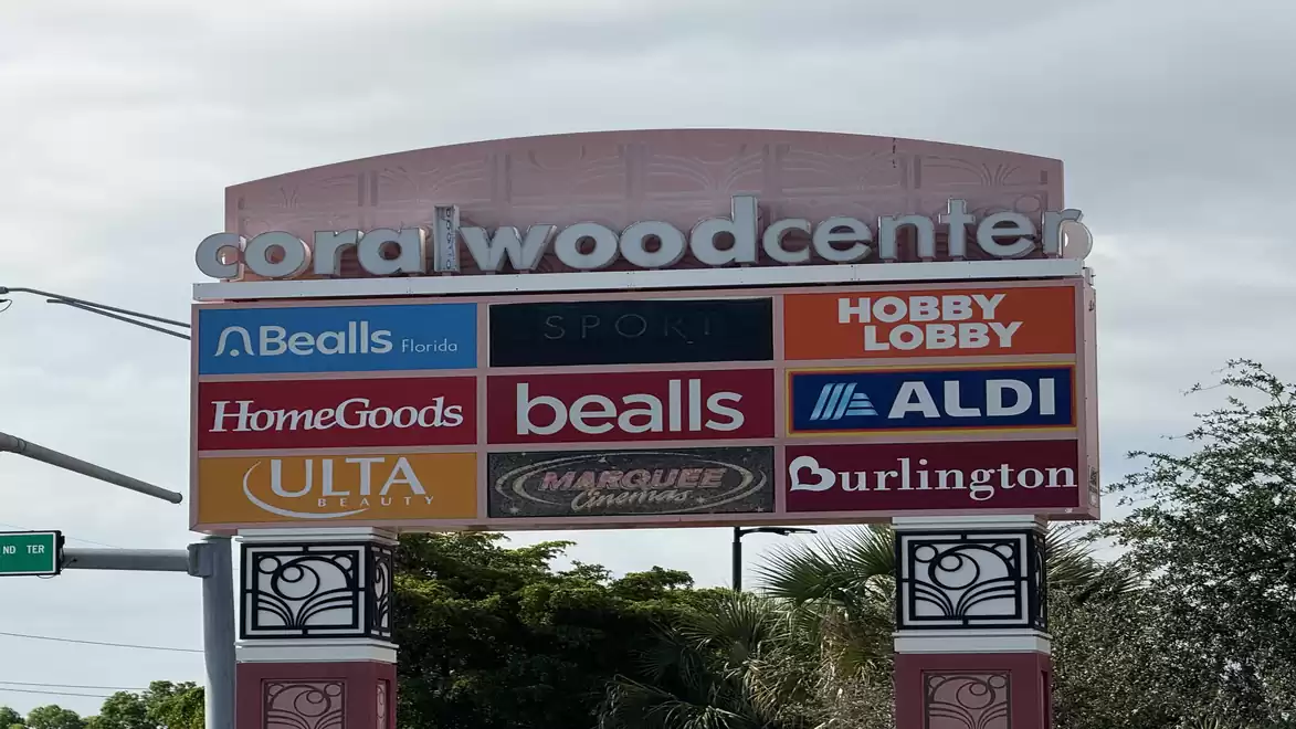 Image of a shopping center sign with logos of various stores like Hobby Lobby, Aldi, and Burlington, labeled as Coralwood Center.