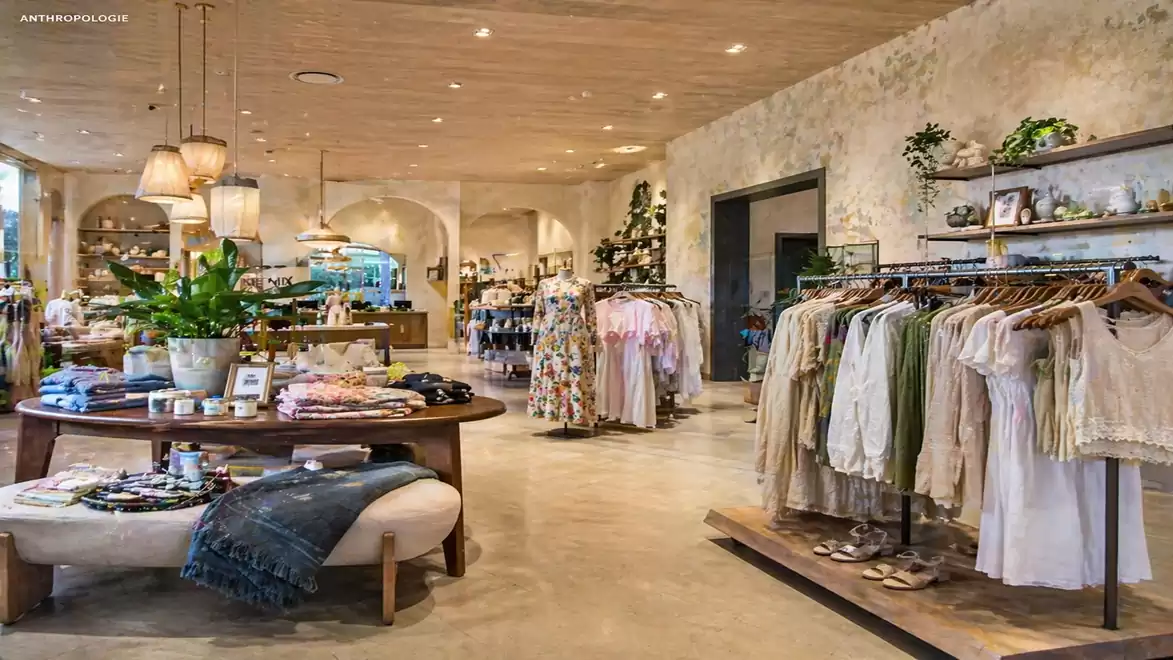 Interior view of a stylishly decorated clothing store with patterned garments, plants, and modern elements.