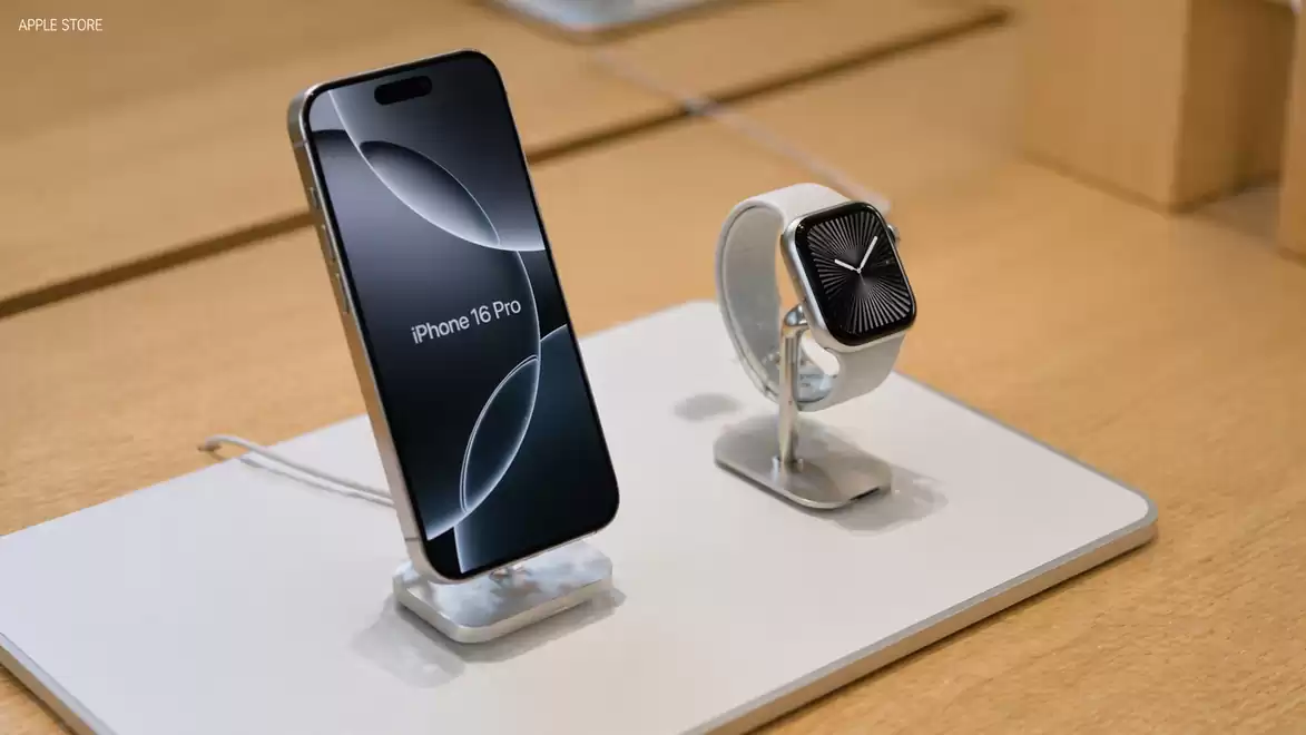 An iPhone 16 Pro and a modern smartwatch are displayed side by side on a display table in a store.