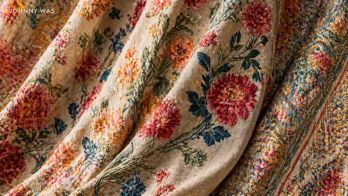 Brightly embroidered fabric with floral patterns in vibrant colors on a beige background.